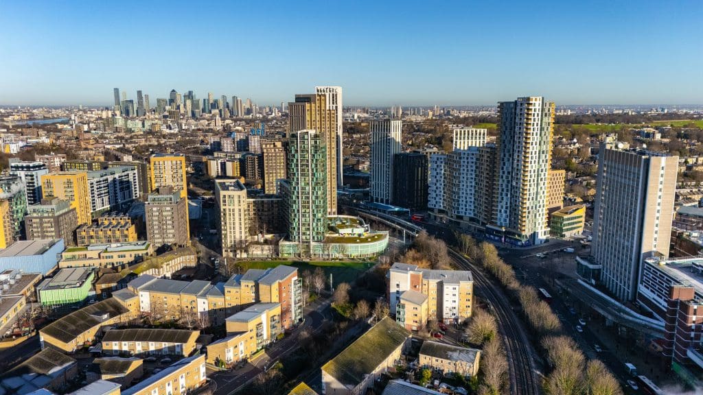 Aerial view of modern high-rise developments in Lewisham, south-east London, with Canary Wharf visible in the background on a clear day.