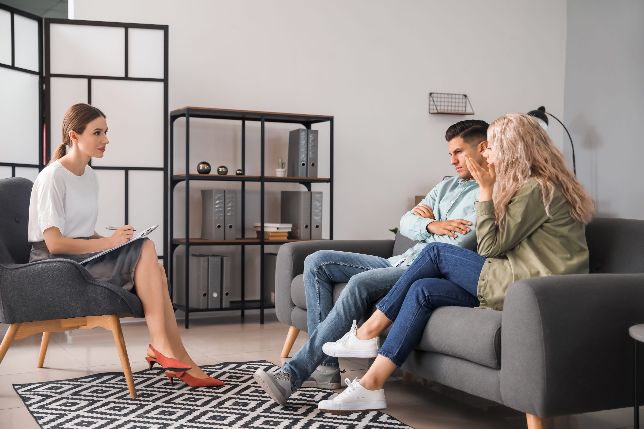 Family mediator taking notes while a separated couple sit together in a calm mediation setting.